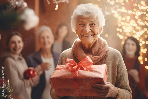 An elderly woman is surrounded by family as she unwraps gifts, demonstrating the importance of family connections in later life