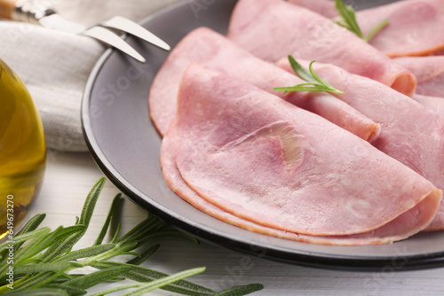 Tasty ham with rosemary and carving fork on table, closeup