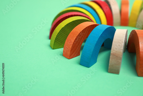 Colorful wooden pieces of play set on green background, closeup with space for text. Educational toy for motor skills development