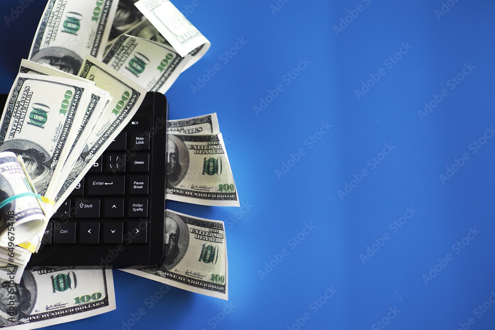 Computer keyboard and a scattering of 100 dollar bills on the table. The work of a programmer and blogger on the Internet. Computer keyboard and a scattering of 100 dollar bills on the table. The work of a programmer and blogger on the Internet.