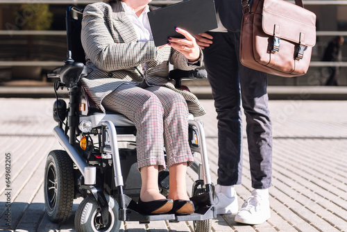 cropped photo of an unrecognizable man and business woman using wheelchair at financial district, concept of diversity and urban lifestyle