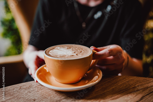 Woman hands holding cup of hot coffee latte cappuccino sit in cafe