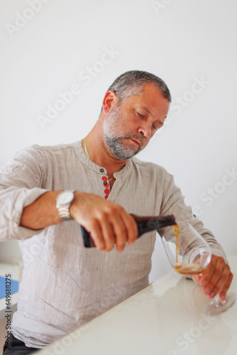 macto of man pouring beer from bottle isolated on white photo