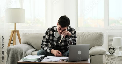 Seated in the living room, a perplexed student displays signs of exhaustion as they grapple with their homework. The scene encapsulates their mental fatigue.
