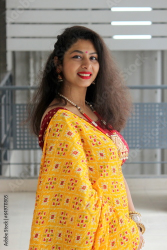 Woman dwearing yello patola dupatta saari with red blouse. she is in traditional festive look with sweet smile. Indian, gujarati model for traditional outfits. 