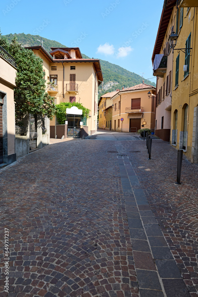 Italy, Lombardia, Canzo, narrow alley at historic old town, against the background of Italian Alps. Street scene. Tourism. Adventure. Trip. Travel destination. Vertical photography