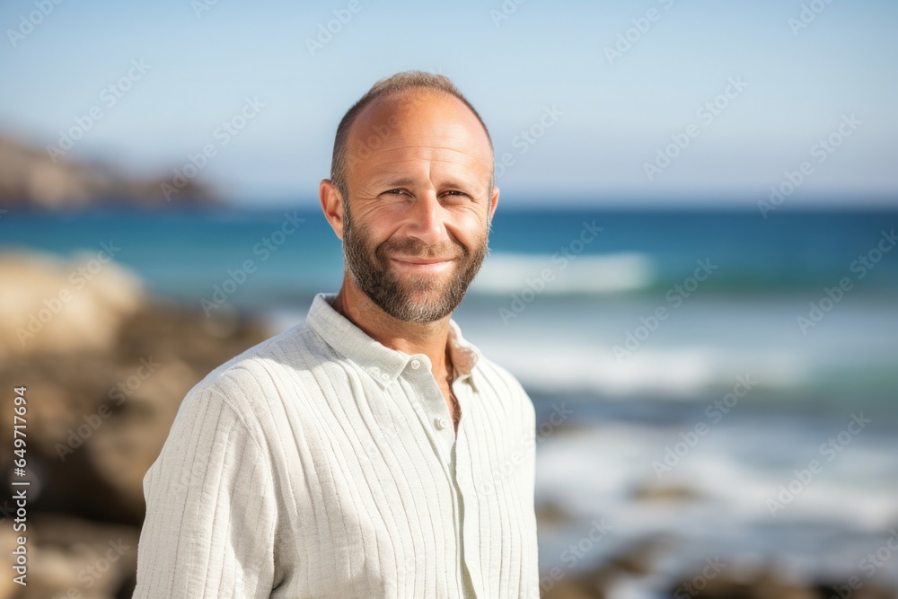portrait of a confident Israeli man in his 40s wearing a chic cardigan against a beach background portrait of a confident Israeli man in his 40s wearing a chic cardigan against a beach background