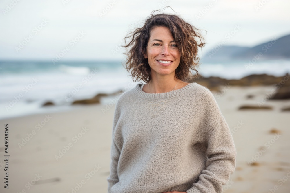 portrait of a confident Israeli woman in her 40s wearing a cozy sweater against a beach background portrait of a confident Israeli woman in her 40s wearing a cozy sweater against a beach background