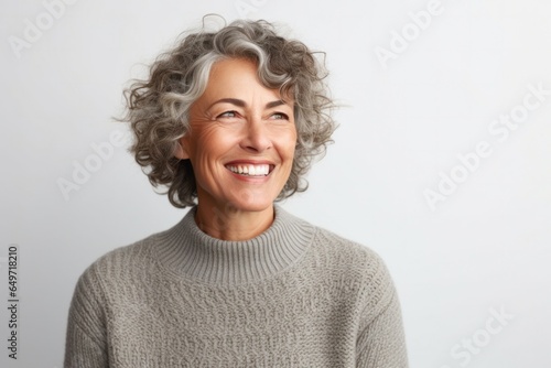 portrait of a confident Israeli woman in her 50s wearing a cozy sweater against a white background