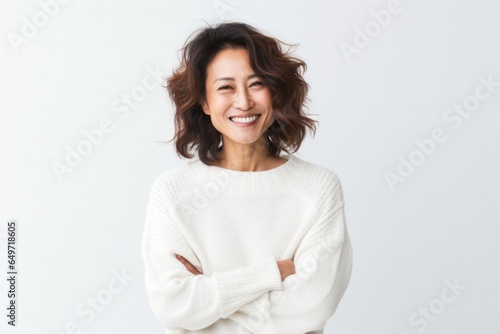 portrait of a confident Japanese woman in her 40s wearing a cozy sweater against a white background