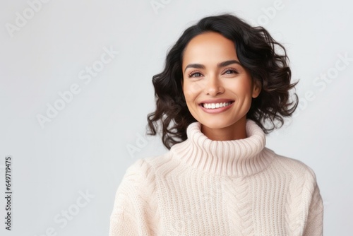 portrait of a confident Mexican woman in her 30s wearing a cozy sweater against a white background
