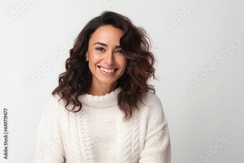 portrait of a confident Mexican woman in her 30s wearing a cozy sweater against a white background