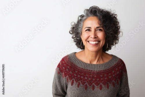 portrait of a confident Mexican woman in her 50s wearing a cozy sweater against a white background