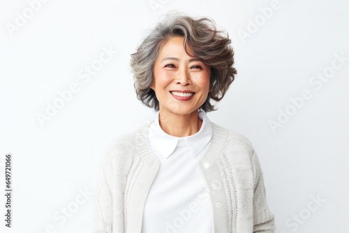Portrait of a Japanese woman in her 50s wearing a chic cardigan against a white background