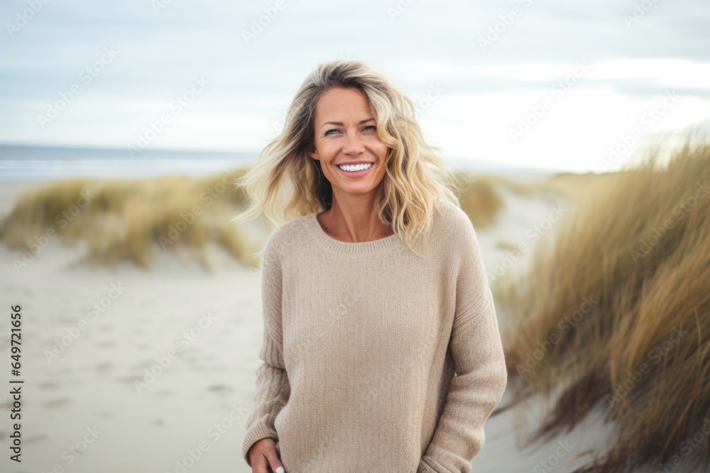 Portrait of a Polish woman in her 40s wearing a cozy sweater against a beach background