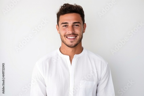 medium shot portrait of a confident Mexican man in his 20s wearing a simple tunic against a white background © Leon Waltz