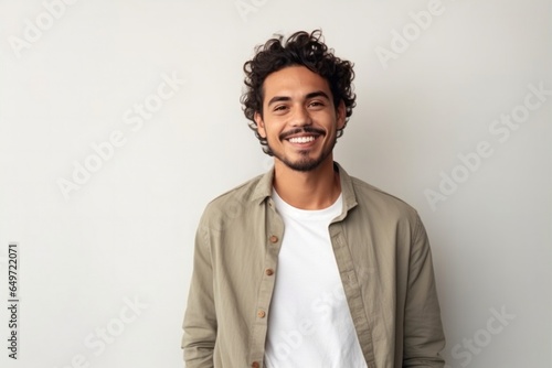 medium shot portrait of a confident Mexican man in his 20s wearing a chic cardigan against a minimalist or empty room background