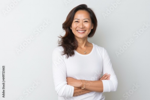 Portrait of a serious, Filipino woman in her 40s wearing a pair of leggings or tights against a white background