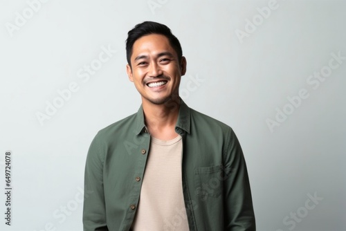 medium shot portrait of a happy Filipino man in his 30s wearing a chic cardigan against a minimalist or empty room background photo