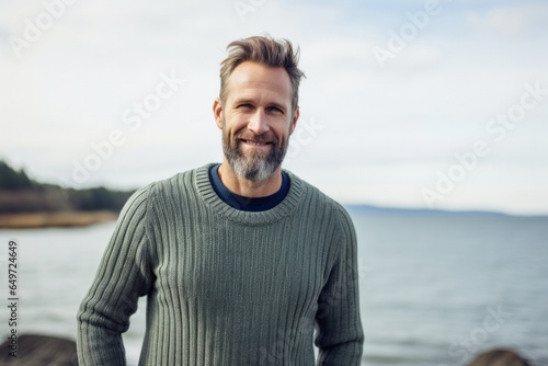 medium shot portrait of a happy Polish man in his 40s wearing a chic cardigan against a beach background