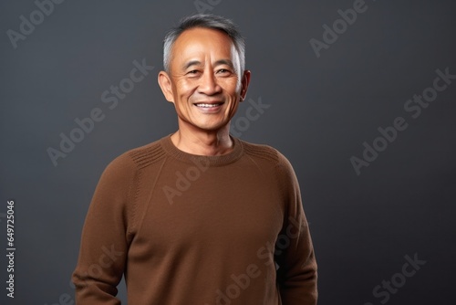 medium shot portrait of a happy Filipino man in his 60s wearing a cozy sweater against an abstract background