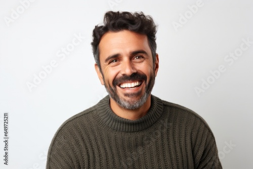 portrait of a happy Mexican man in his 30s wearing a cozy sweater against a white background