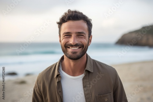 medium shot portrait of a happy Israeli man in his 30s wearing a chic cardigan against a beach background