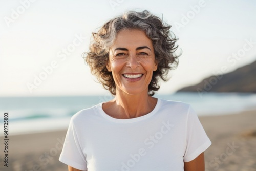 medium shot portrait of a happy Israeli woman in her 60s wearing a sporty polo shirt against a beach background
