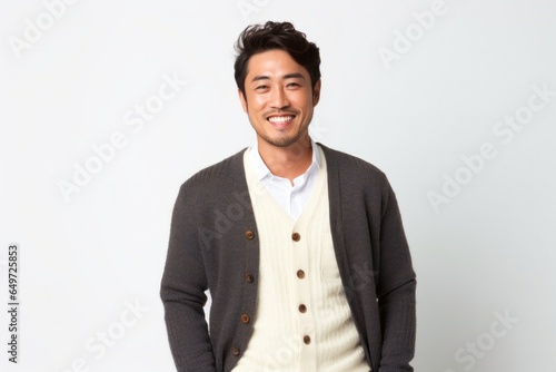 medium shot portrait of a happy Japanese man in his 30s wearing a chic cardigan against a white background