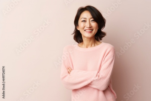 medium shot portrait of a happy Japanese woman in her 40s wearing a cozy sweater against a pastel or soft colors background