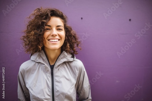 portrait of a happy Israeli woman in her 30s wearing a lightweight windbreaker against an abstract background photo
