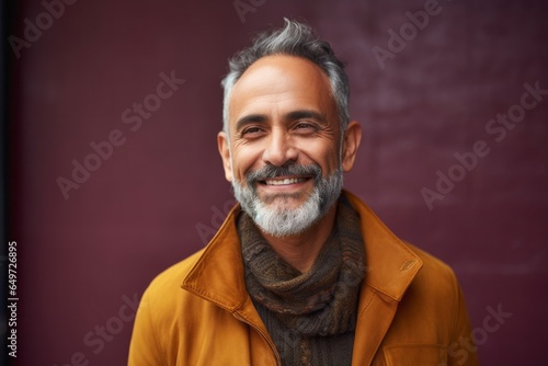 medium shot portrait of a happy Mexican man in his 50s wearing a chic cardigan against an abstract background