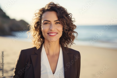 medium shot portrait of a happy Mexican woman in her 40s wearing a classic blazer against a beach background