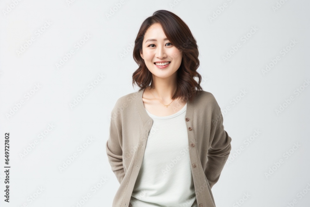 portrait of a happy Japanese woman in her 30s wearing a chic cardigan against a white background