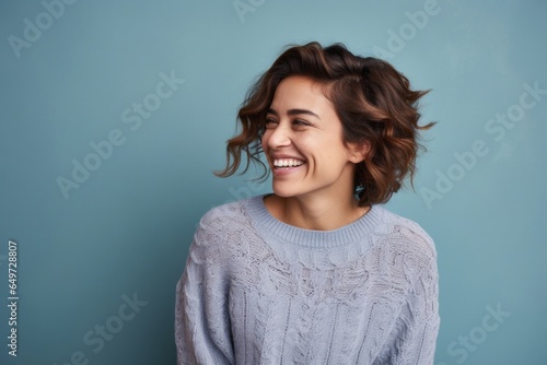 portrait of a happy Mexican woman in her 30s wearing a cozy sweater against an abstract background © Leon Waltz