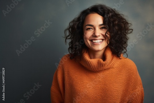 portrait of a happy Mexican woman in her 30s wearing a cozy sweater against an abstract background © Leon Waltz