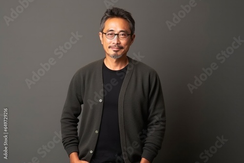 medium shot portrait of a Japanese man in his 40s wearing a chic cardigan against a minimalist or empty room background © Anne-Marie Albrecht