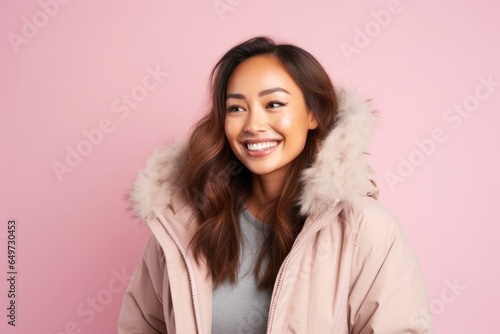 portrait of a Filipino woman in her 30s wearing a warm parka against a pastel or soft colors background © Leon Waltz