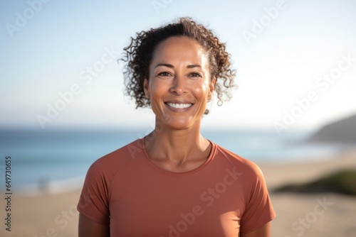 portrait of a Filipino woman in her 40s wearing a sporty polo shirt against a beach background © Leon Waltz
