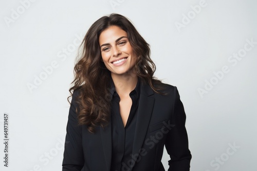 portrait of a Israeli woman in her 30s wearing a sleek suit against a white background