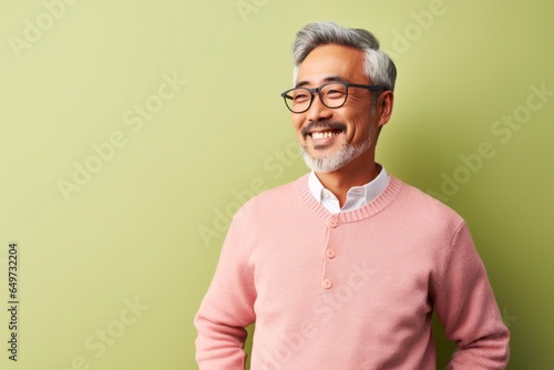 portrait of a Japanese man in his 50s wearing a chic cardigan against a pastel or soft colors background