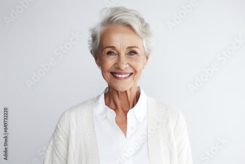 medium shot portrait of a Polish woman in her 70s wearing a chic cardigan against a white background