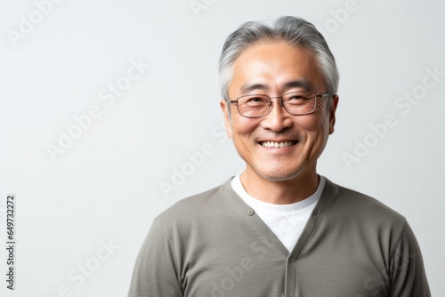 portrait of a Japanese man in his 50s wearing a chic cardigan against a white background