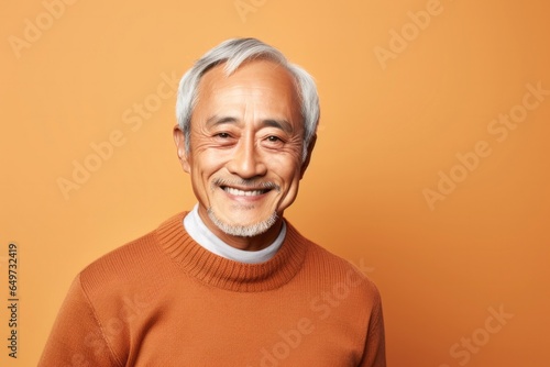 portrait of a Japanese man in his 70s wearing a cozy sweater against a pastel or soft colors background © Leon Waltz