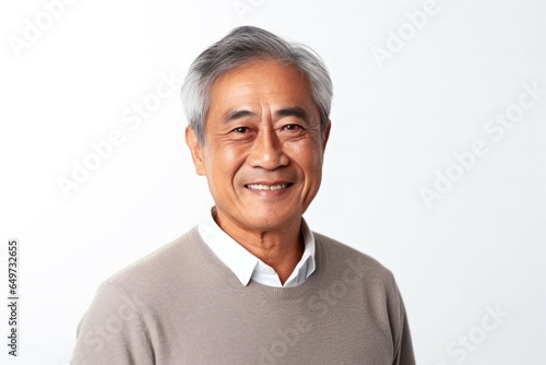 medium shot portrait of a confident Filipino man in his 60s wearing a chic cardigan against a white background