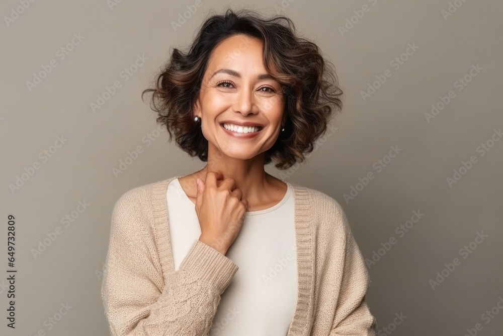 medium shot portrait of a confident Filipino woman in her 40s wearing a chic cardigan against an abstract background medium shot portrait of a confident Filipino woman in her 40s wearing a chic cardigan against an abstract background