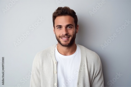 medium shot portrait of a confident Israeli man in his 20s wearing a chic cardigan against a minimalist or empty room background