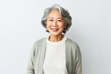 medium shot portrait of a confident Japanese woman in her 50s wearing a chic cardigan against a white background