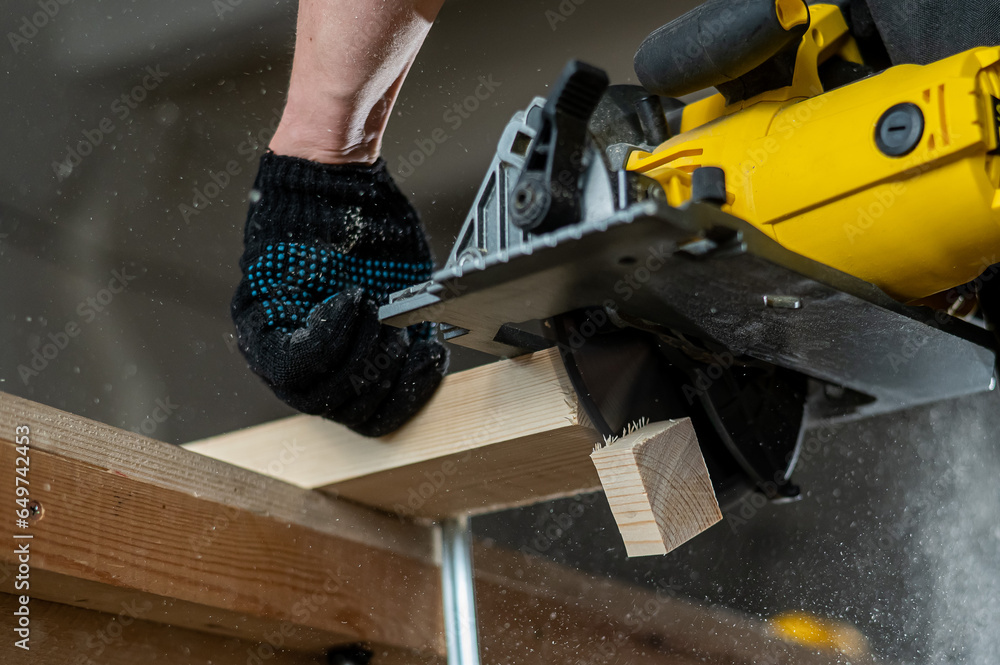 Master cuts the board with a circular saw in the workshop. Close-up of a carpenter's hands at work. Master cuts the board with a circular saw in the workshop. Close-up of a carpenter's hands at work.