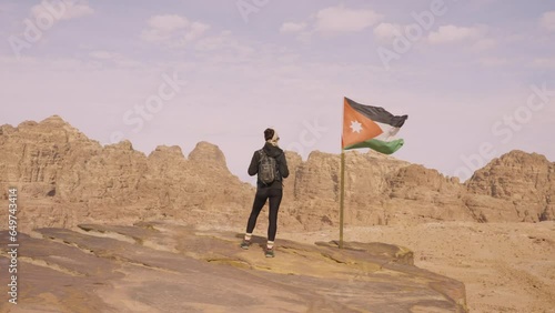 Woman walking towards a viewpoint in Petra. Jordanian flag waving.